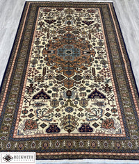 A hand-knotted wool on cotton foundation Ardebil rug with a floral and geometric pattern in beige, brown, and multicolor.