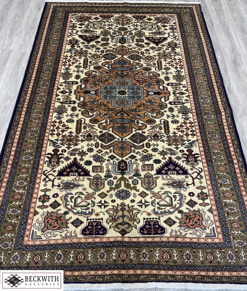 A hand-knotted wool on cotton foundation Ardebil rug with a floral and geometric pattern in beige, brown, and multicolor.
