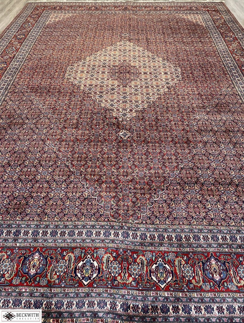 An oversized, hand-knotted Sarab rug with a geometric pattern, predominantly in red and blue colors, showcasing intricate detailing.