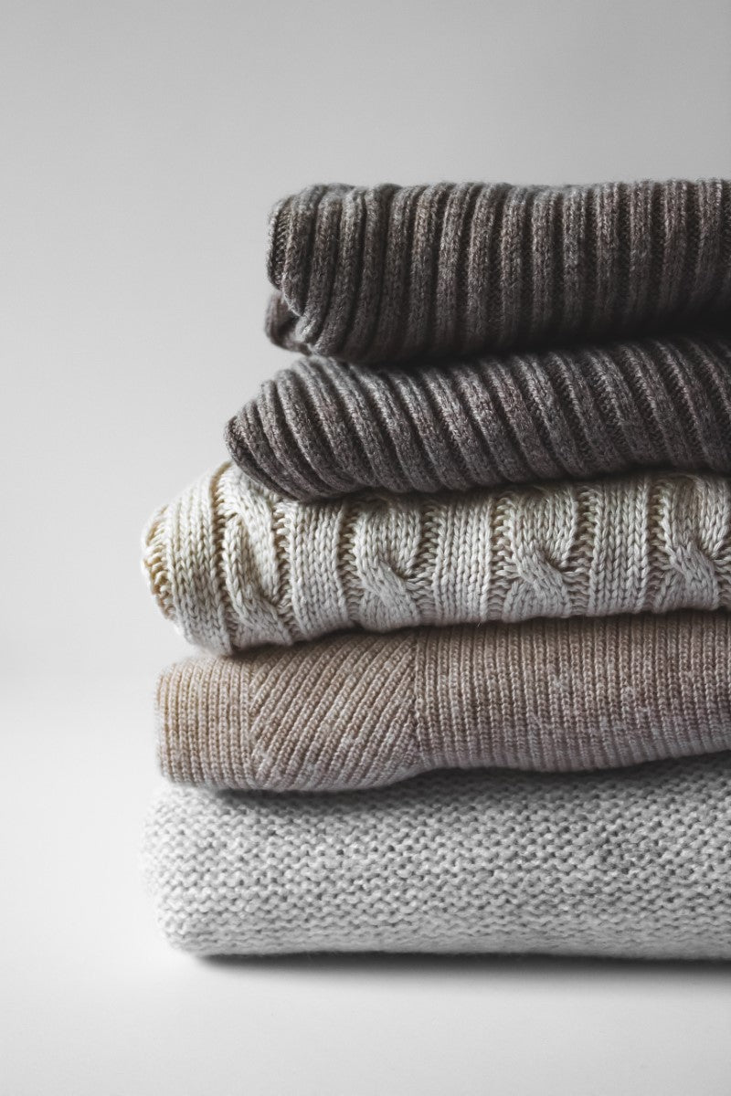 Knitted wool textiles. Cosy and warm sweaters on white background. Photographer © Tijana Drndarski