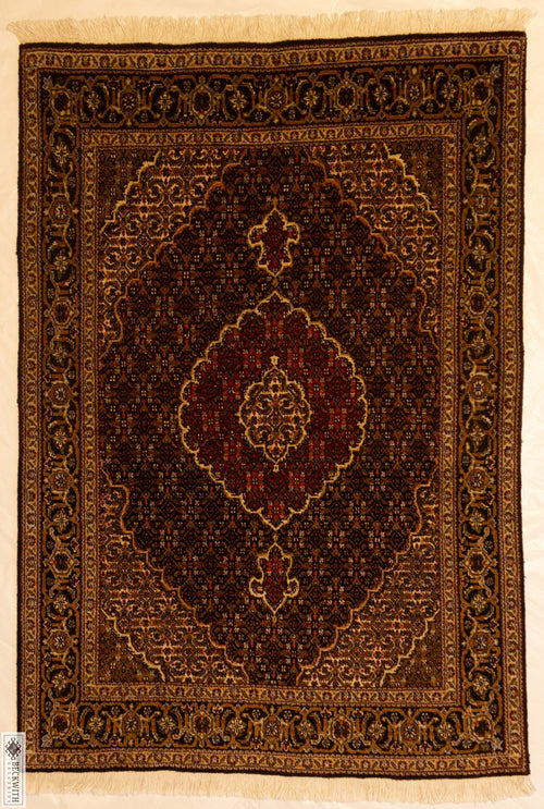 A rectangular traditional Tabriz rug with a geometric and floral pattern in brown, black, gold, and cream colors.